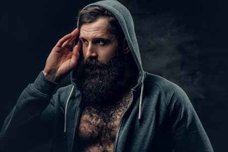 Portrait of brutal bearded male with tattoo on a chest, dressed in a grey hoodie.の写真素材