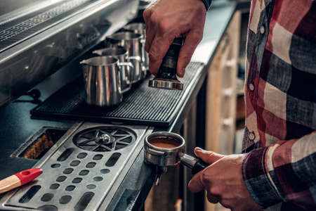 Close up image of a man making coffee in a professional coffee machine.の写真素材