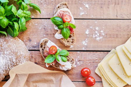 Healthy brown bread with ham, cheese and tomatoes on a wooden table.