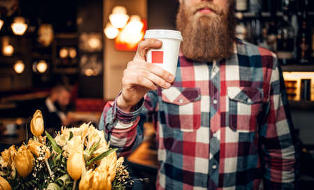 Redhead bearded male dressed in a fleece shirt posing at the counter in a coffee shop.の写真素材