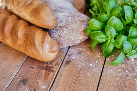 Delicious white bread and green basil on a wooden table.の写真素材