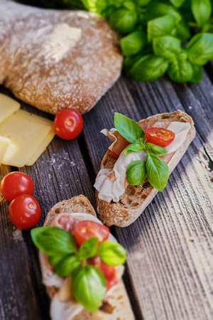 Healthy brown bread with ham, cheese and tomatoes on a wooden table.の写真素材