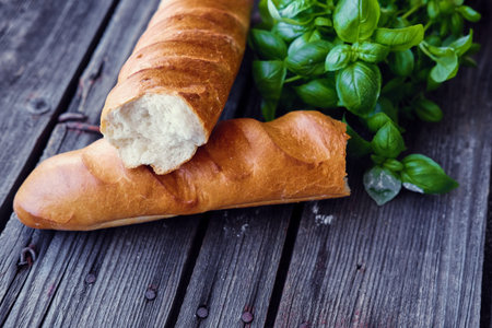 French baguette and green basil on a grey wooden table.