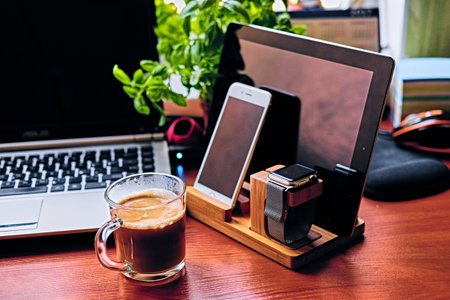 Communication set with smart watch, tablet PC, computer and a cup of coffee on a table.の写真素材