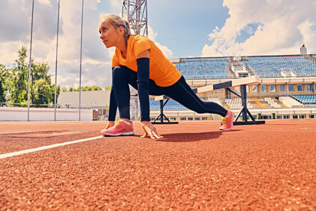 Blond sporty female stretching on a stadium field.の写真素材
