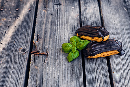 Delicious chocolate eclairs with berries on a grey wooden table.