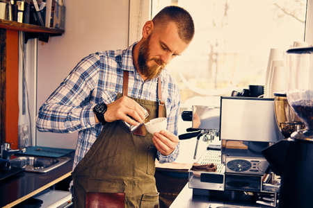 A man preparing cappuccino in a coffee shop.の写真素材