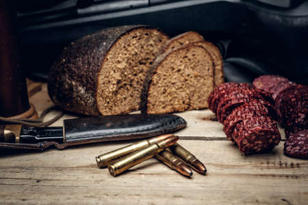 Delicious sausage, brown bread and gun cartridge on a wooden table.の写真素材