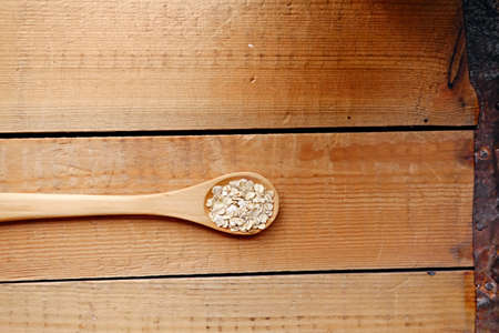 Wooden spoon with oat flakes over wooden pattern background.の写真素材