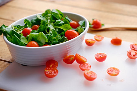 Cutted cherry tomatoes and basil salad on a white plate.の写真素材