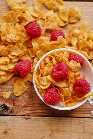 Dieting gold, corn flakes with raspberry on a wooden table.の写真素材