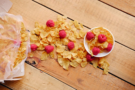 Dieting gold, corn flakes with raspberry on a wooden table.