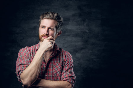 Studio portrait of blond bearded male dressed in a red fleece shirt over dark grey background.の写真素材