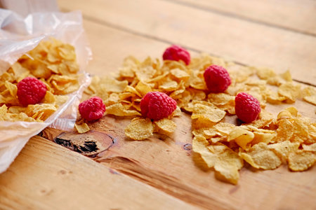 Dieting gold, corn flakes with raspberry on a wooden table.の写真素材