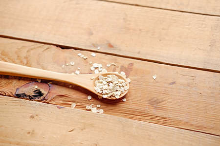 Wooden spoon with oat flakes over wooden pattern background.の写真素材