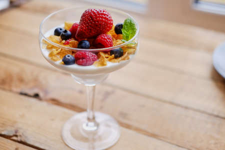 Gold crunchy corn flakes with some wild berries in a glass cup.の写真素材
