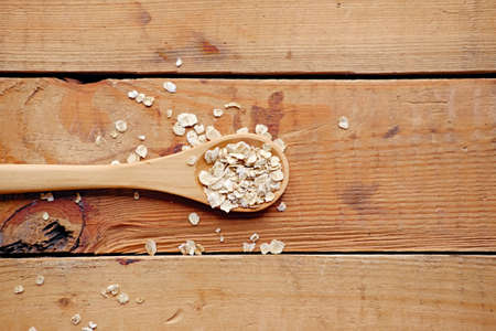 Wooden spoon with oat flakes over wooden pattern background.の写真素材