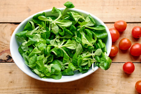 Cherry tomatoes and basil salad in a white cup on a wooden table.の写真素材