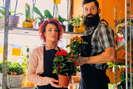 Redhead female and bearded tattooed male selling flowers in a market shop.の写真素材