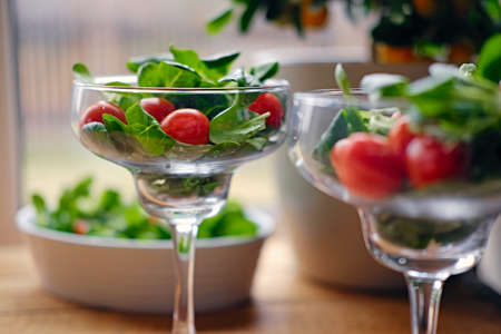 Cherry tomatoes and basil salad on a glass cup on a wooden table.の写真素材