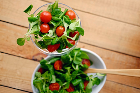 Cherry tomatoes and basil salad on a plate with a pot on a wooden table.の写真素材