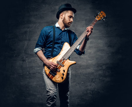 Studio portrait of the hipster bass player dressed in cylinder hat.の写真素材