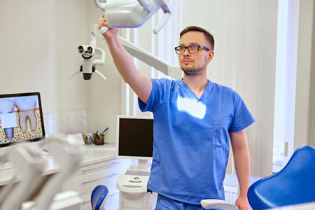 Handsome male dentist in a room with medical equipment on background.の写真素材