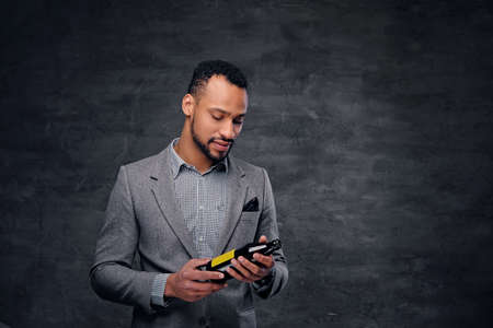 Portrait of stylish black American male dressed in a grey suit holds a craft beer bottle.の写真素材
