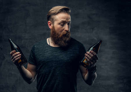 Emotional, funny redhead bearded drunk hipster male holds craft bottled beer.の写真素材