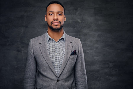 Classic studio portrait of black American male dressed in a suit over grey vignette background.