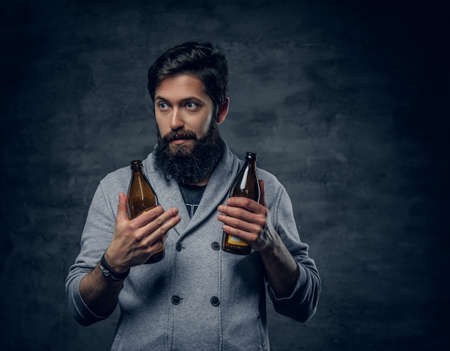 Full throttle bearded male holds two craft beer bottles.の写真素材