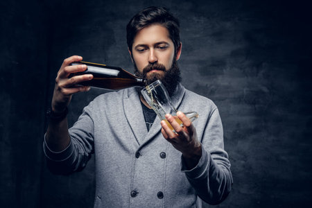 Full throttle bearded male pouring draft beer into the glass from craft bottle.の写真素材