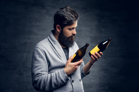 Full throttle bearded male holds two craft beer bottles.の写真素材