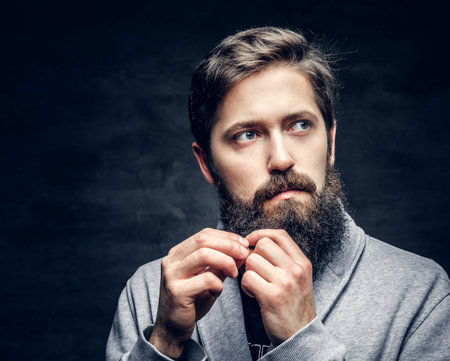 Studio portrait of full throttle bearded male touching his hair over grey background.の写真素材