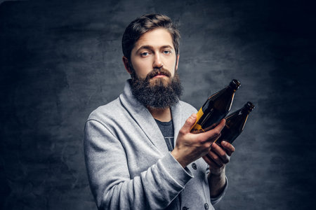 Full throttle bearded male holds two craft beer bottles.の写真素材