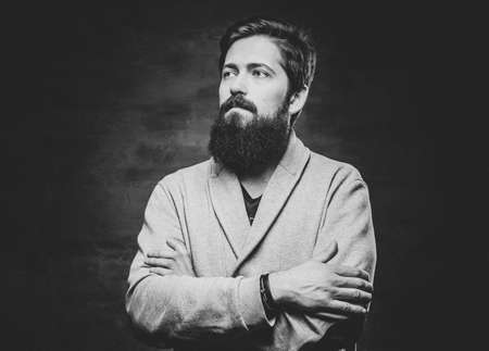 Studio portrait of full throttle bearded male with crossed arms over grey background.の写真素材