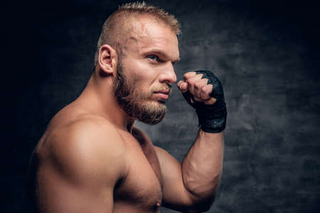Studio portrait of brutal bearded fighter over dark grey background.の写真素材