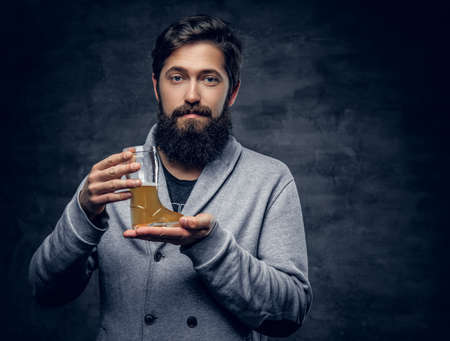 Studio portrait of bearded male holds a glass with pale ale beer.の写真素材