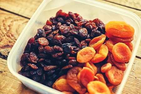 Diet food. Raisins and dried apricots on a wooden table.