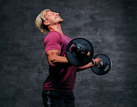 Emotional, screaming, athletic, blond male doing a biceps workout with a barbell.