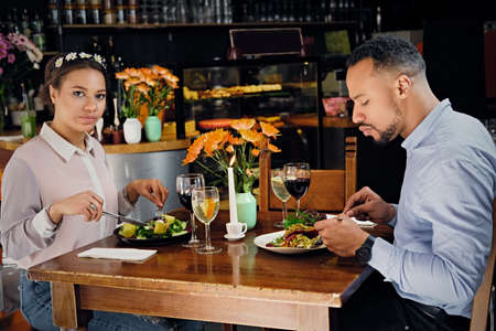 Black American male and female eating vegan food in a restaurant.の写真素材
