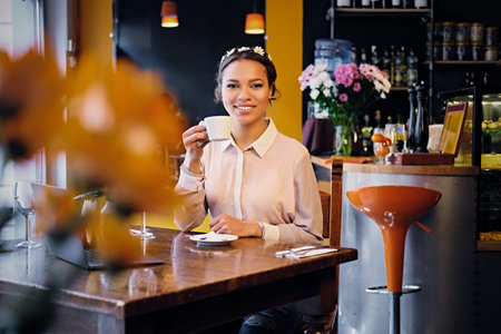 Portrait of a black American male using a laptop and drink coffee in a cafe.の写真素材