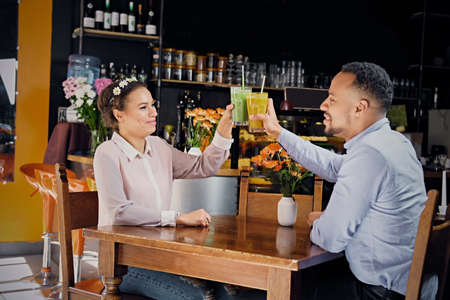 Black American couple talks and drinks, fresh juice at a cafeの写真素材