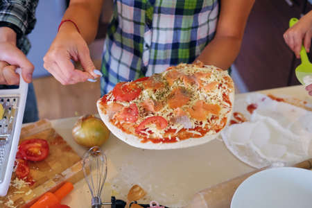 Attractive couple of brunette female and a male in fleece shirt cooking the food in a home family kitchen.の写真素材