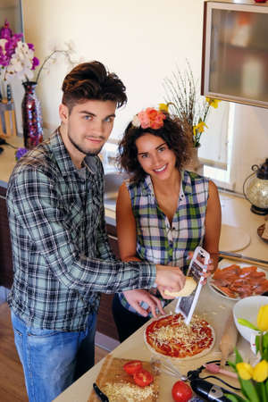 Attractive couple of brunette female and a male in fleece shirt cooking the food in a home family kitchen.の写真素材