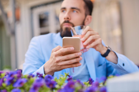 Stylish bearded male in a blue jacket using smartphone.