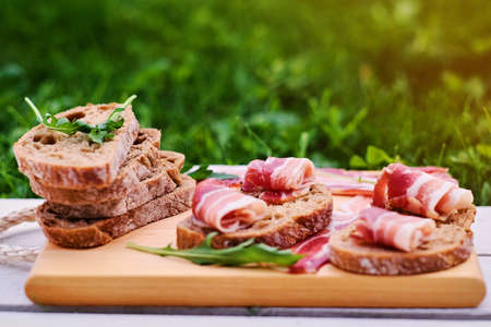 Bread with gourmet meat on a wooden desk over green lawn background.の写真素材