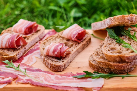 Bread with gourmet meat on a wooden desk over green lawn background.の写真素材