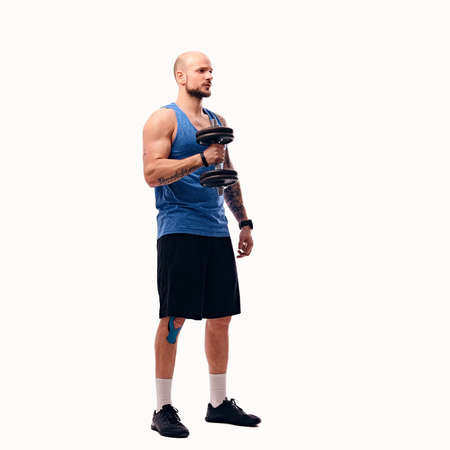 Full body image of shaved head athletic male holds dumbbells isolated on a white background.の写真素材
