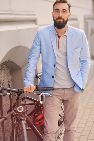 Portrait of elegant bearded guy near the retro bicycle in an old town.の写真素材